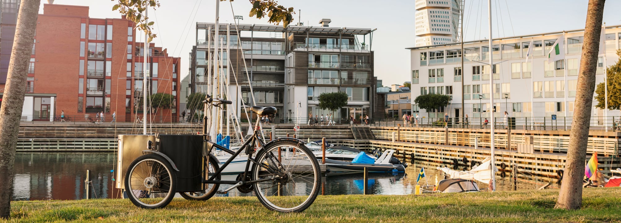Cykel vid småbåtshamn i ett storstadsområde.
